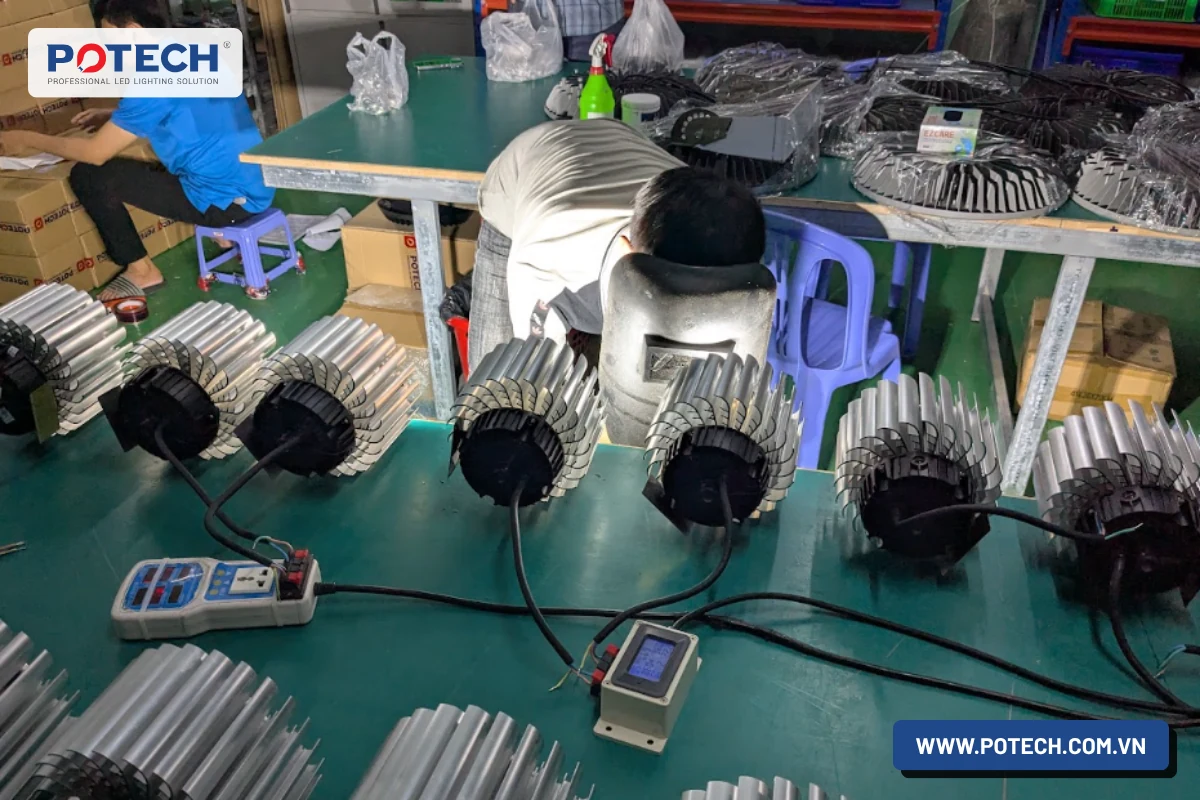 Thợ kiểm tra điện từng bộ đèn LED highbay bằng đồng hồ đo tại xưởng sản xuất POTECH
